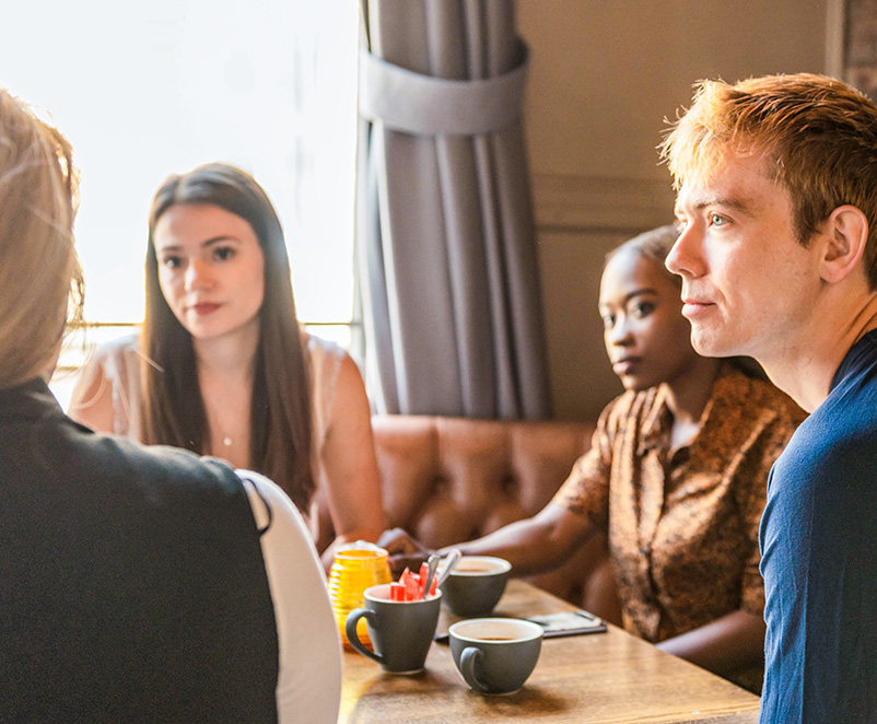 Photograph of 4 people around a table having a discussion